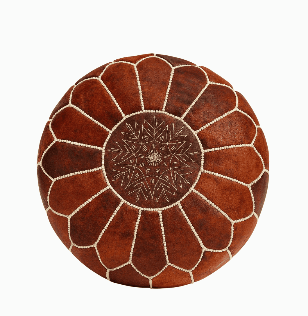 Round brown leather ottoman with decorative stitching on a white background